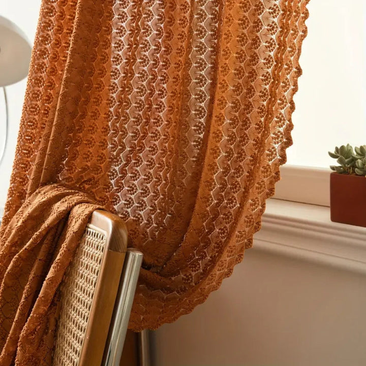 Lichtdurchlässiger Häkelvorhang im Boho-Stil vor einem Fenster