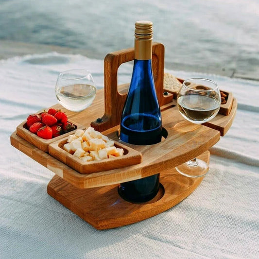 Tragbarer Picknicktisch aus Holz mit Weinflasche, Gläsern, Käse und Erdbeeren.