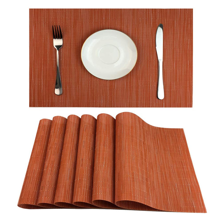 Sechs orange Platzsets für eine herbstliche Tischdekoration auf einem gedeckten Tisch