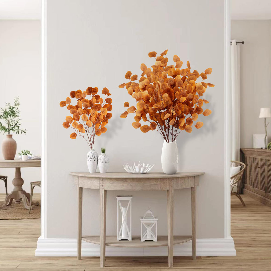 Set aus sechs künstlichen Eukalyptusblättern in Orange auf hellem Hintergrund