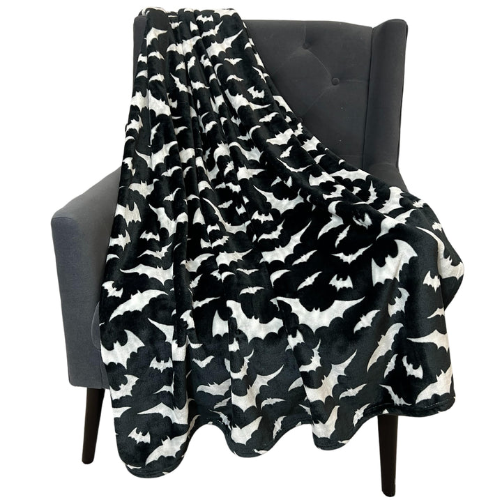 Schwarze Halloween-Decke mit silbernen Fledermäusen auf einem Sofa