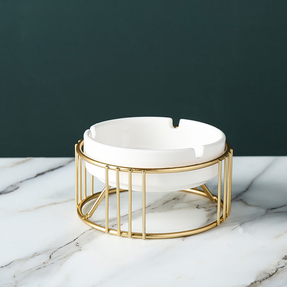 Weißer Keramik-Aschenbecher mit goldfarbenem Metallständer auf neutralem Hintergrund