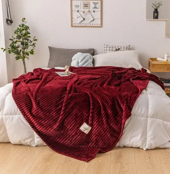 Weiche Wohndecke aus Flanell auf einem Bett im gemütlichen Schlafzimmer