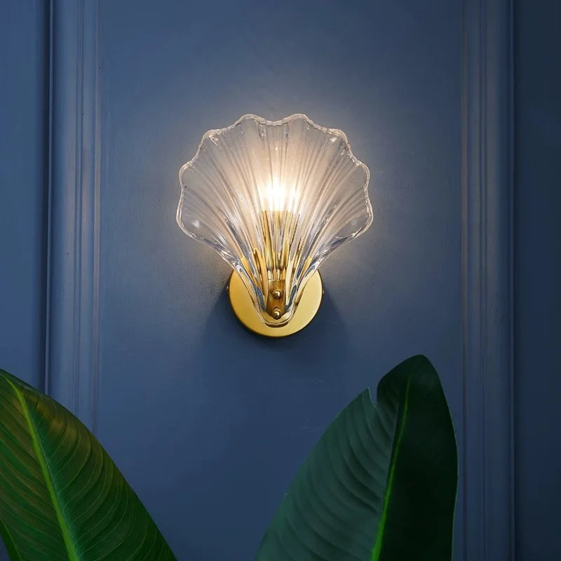 Wandleuchte aus Glas in Muschelform mit E14-Fassung an einer hellen Wand