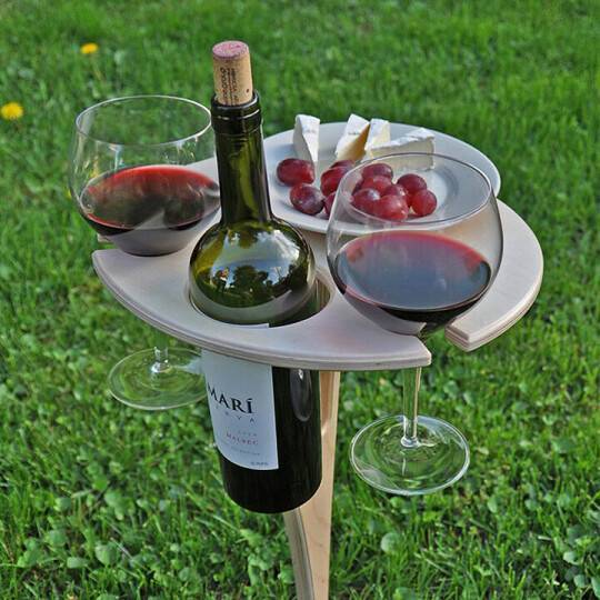 Klappbarer Picknicktisch aus Holz mit Weinglashalter aufgestellt im Freien