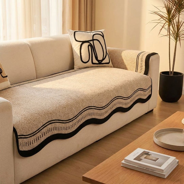 Rutschfester Sofabezug aus Chenille mit Fischgrätmuster auf einem hellen Sofa